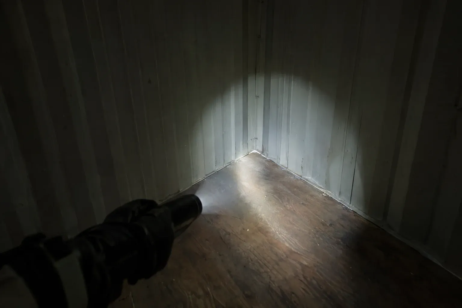 A flashlight beam inside an empty container checking a corner for leaks