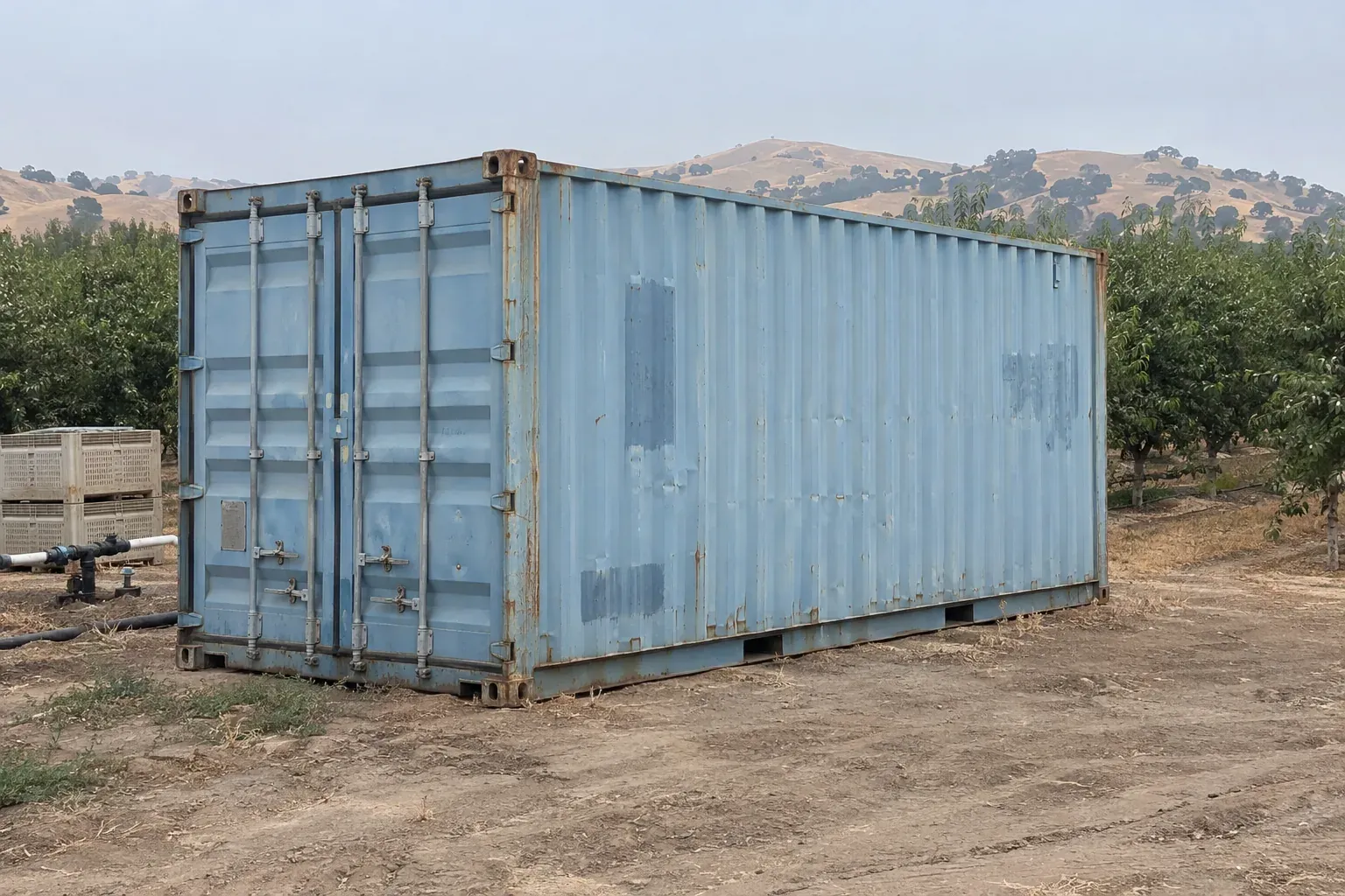 Used light blue 20ft container at the edge of an orchard outside California