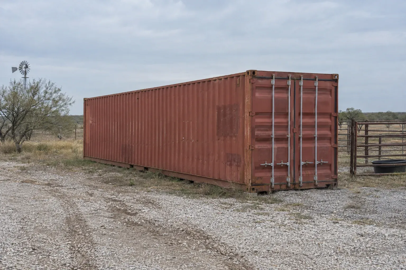 Used rust-red 40ft container by a pipe corral on a ranch outside Nebraska