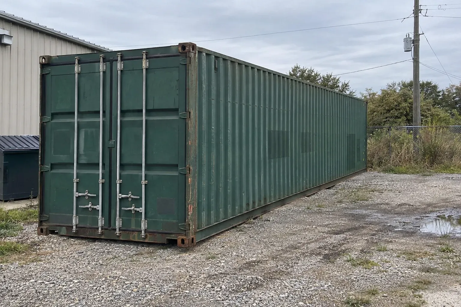 Used green 40ft high cube behind a small metal shop building in New Jersey
