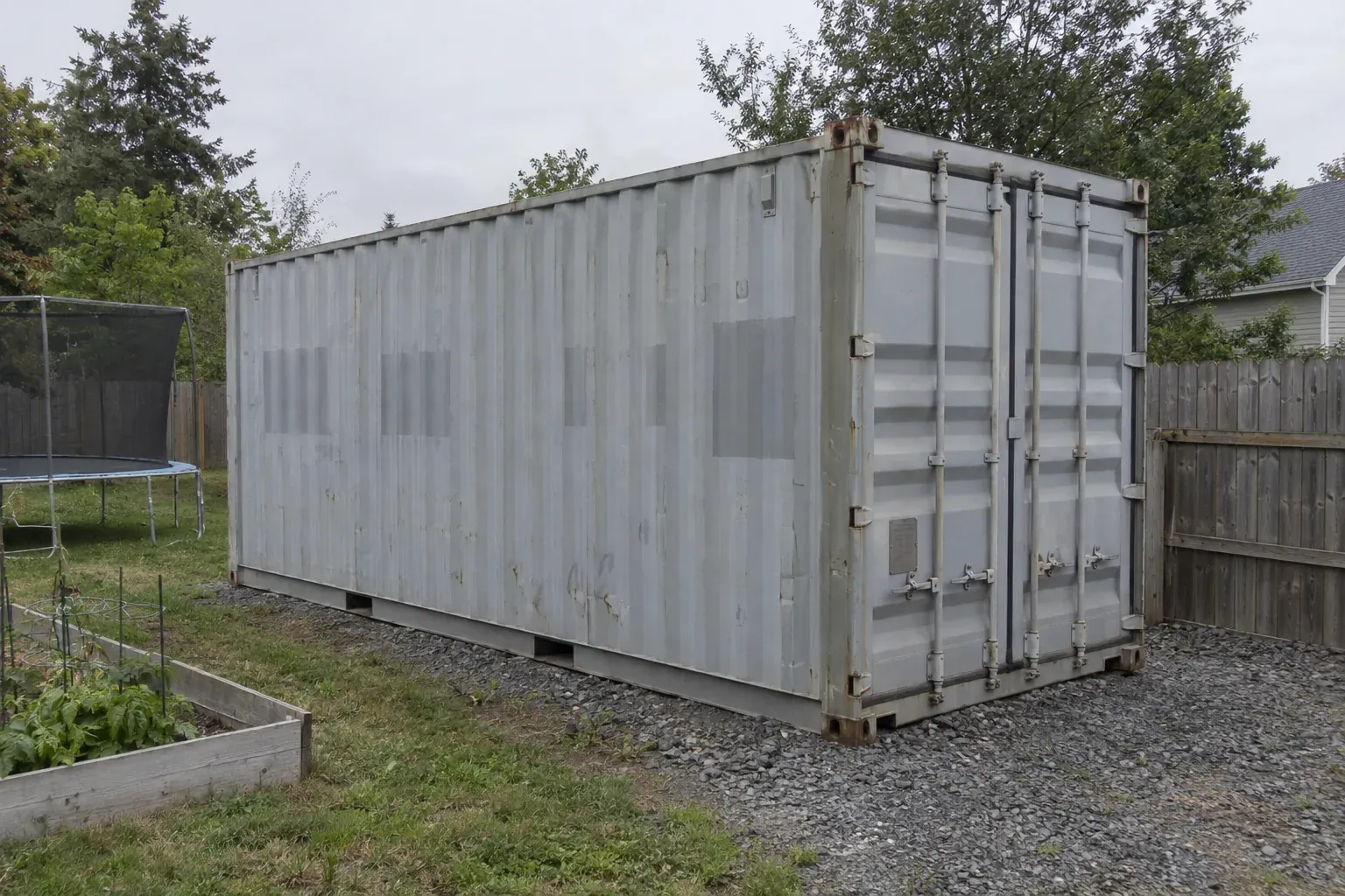 Used grey 20ft container on a gravel pad in a fenced backyard in Virginia